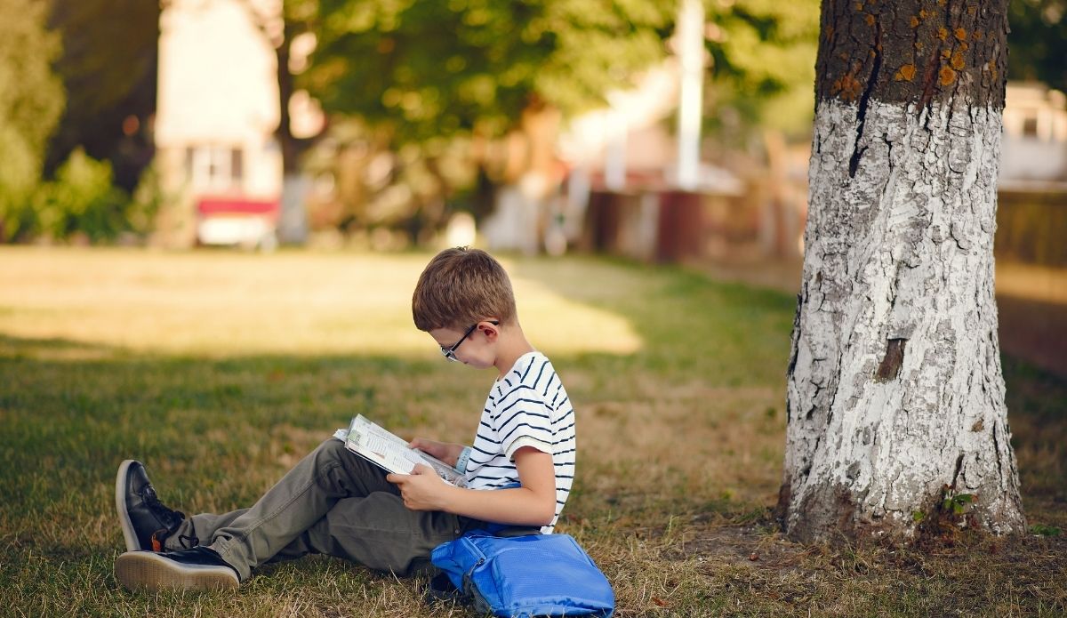Kids outside A boy reading a book outside